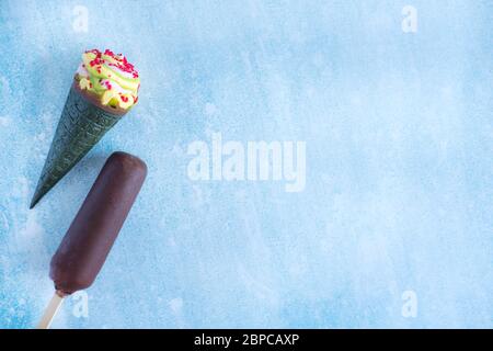 Ice cream in chocolate, ice cream cone with green waffle and bright crumbs. A few ice creams on a blue background Stock Photo