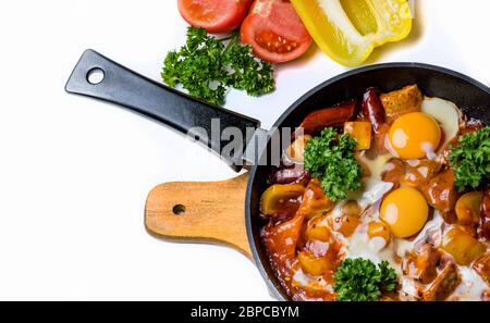Hearty breakfast, delicious hot omelette with vegetables and sausage, served in a pan, fresh vegetables are nearby. Isolated on White Background Stock Photo
