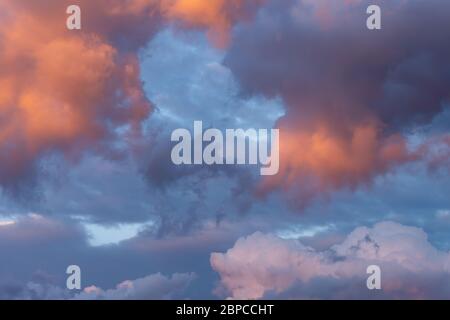 colorful fluffy purple and pink cumulus clouds against a blue sky in the evening sunset Stock Photo