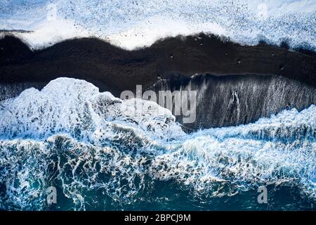 Drone view of tidal waves rolling on snowy seashore on sunny day in Iceland Stock Photo