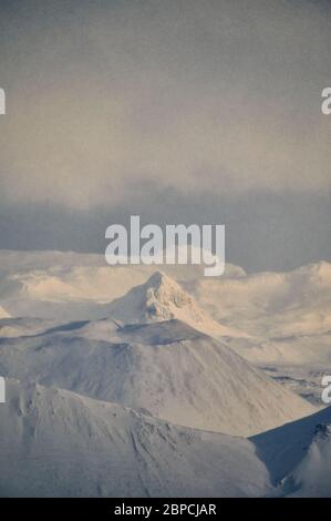 Magnificent drone view of highlands in evening under cloudy sky during sunset in winter Stock Photo