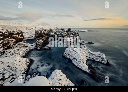 Aerial view of breathtaking seascape with rough stones covered with snow and located in sea water in Iceland Stock Photo