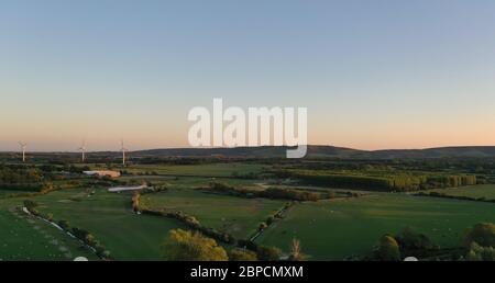 beautiful British countryside view showing green fields, forest, farmland, wind turbines, and the south downs in the distance Stock Photo