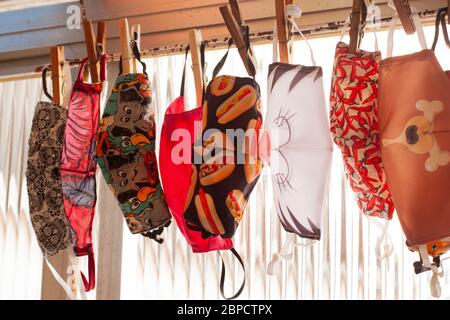 Eight colorful and stylish protective face masks hanging out to dry in clothesline Stock Photo