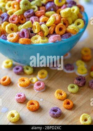 Colourful bowl of cereal spilling over wooden table top. Stock Photo