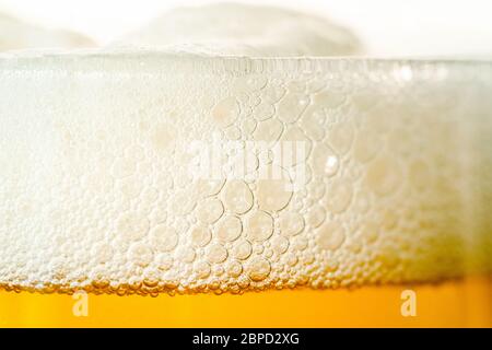 Craft beer glass with bubble froth close up, refreshing cold drink background. Stock Photo