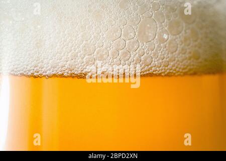 Craft beer glass with bubble froth close up, refreshing cold drink background. Stock Photo