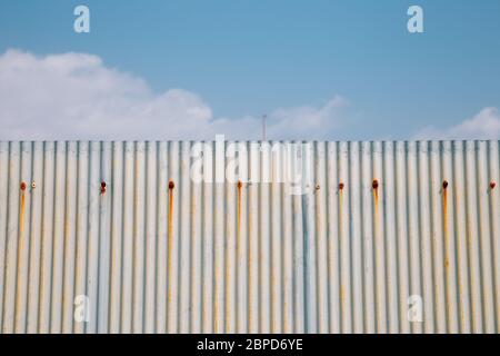 Gray rusty wavy metal plate wall with sky blue background Stock Photo
