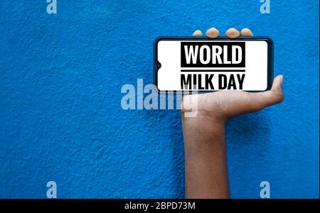1st June - World Milk Day wording on the smart phone mobile screen with isolated on blue background. World Milk Day wording. Stock Photo