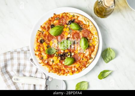 Tasty salami pizza. Pizza with basil leaves on plate. Top view. Stock Photo