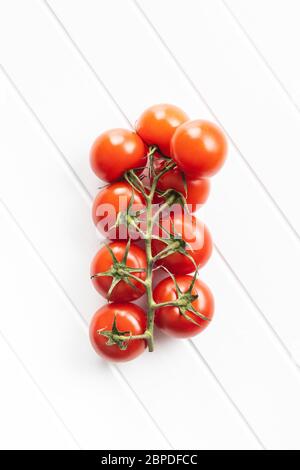 Branch of red cherry tomatoes on white table. Top view. Stock Photo