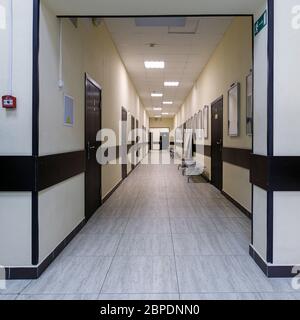 empty corridor in the modern office building. There are many brown doors along a very long corridor with beige walls. Stock Photo