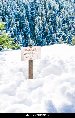 danger sheer cliff keep off sign on the edge of land cover with snow.. Stock Photo