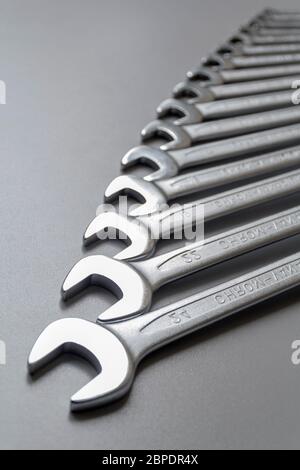 Spanners. Many wrenches. Grey background. Set of wrenches in different sizes on grey background. Vertical format. Stock Photo