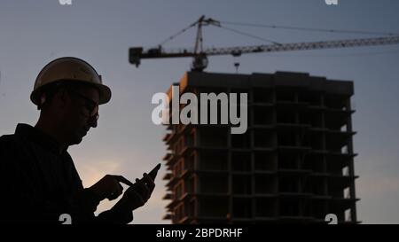 Engineer at the construction site using his phone texting someth Stock Photo