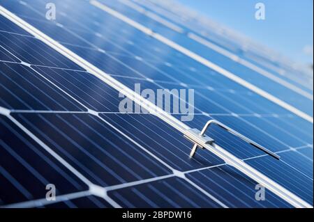 Close-up snapshot of a new blue shiny solar module and a hex key stuck in between. Green energy concept. Modern technologies, ecological solution, power sustainable resources concept