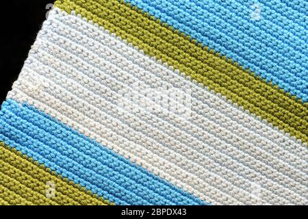 Fragment of crocheted fabric from green, blue and light blue threads close-up, top view. Abstract background. Hand made concept Stock Photo