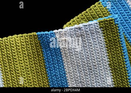 Fragment of crocheted fabric from green, blue and light blue threads close-up, top view. Abstract background. Hand made concept Stock Photo