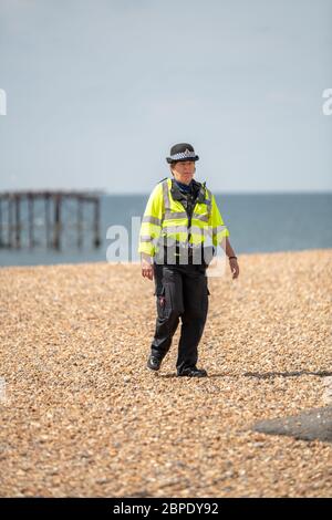 A community support officer patrols a largely empty Brighton beach, Brighton, East Sussex. Stock Photo