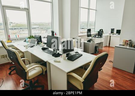 Interior of empty modern office with desktop computers on tables placed near each other, coronavirus quarantine concept Stock Photo