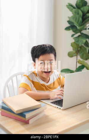 Asia preteen boy studying online on laptop with smiling and fun face at home. online education and e-learning concept. Stock Photo