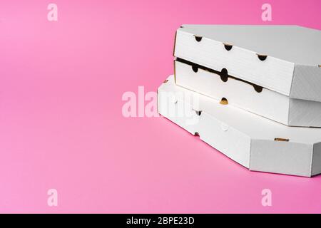 White cardboard pizza delivery boxes on pink background Stock Photo