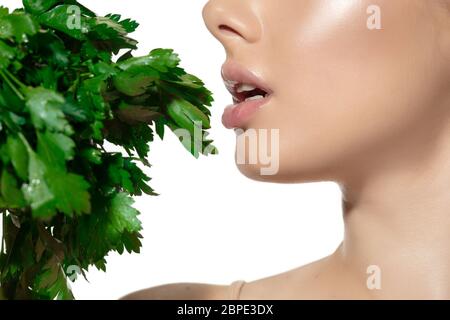 Close up of beautiful young woman with green leaves over white background. Concept of cosmetics, makeup, natural and eco treatment, skin care. Shiny and healthy skin, fashion, healthcare. Stock Photo