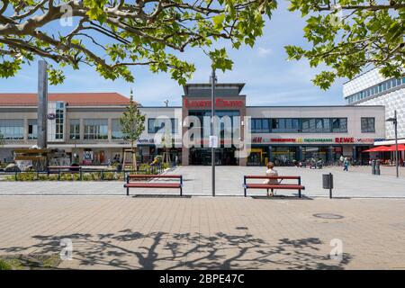 Hoyerswerda, Germany. 18th May, 2020. An elderly woman is sitting on the park bench at the Lausitz Center on Lausitzer Platz in the centre of the Saxon city of Hoyerswerda. Between the park benches a distance of 1.50m is indicated on the lantern. Credit: Daniel Schäfer/dpa-Zentralbild/Daniel Schäfer/dpa/Alamy Live News Stock Photo