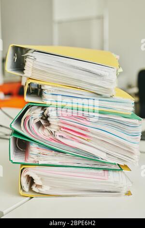 Close-up of table with stack of colorful folders full of files with attached adhesive notes in office Stock Photo
