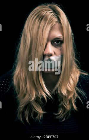 Portrait of scared kidnapped woman hostage with tape over her mouth Stock Photo