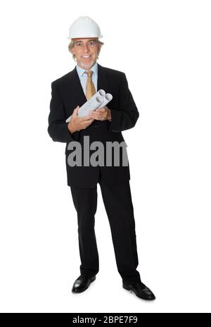 Middle aged businessman wearing hardhat holding blueprints on white background. Stock Photo