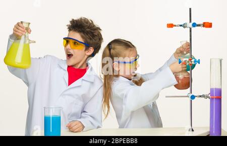 Two cute children at chemistry lesson making experiments on white background Stock Photo