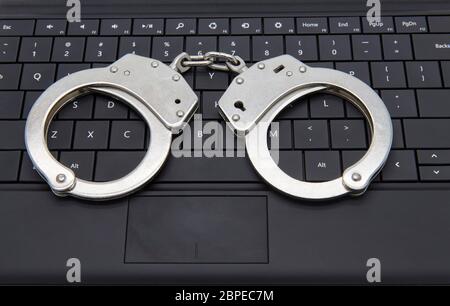 Handcuffs on laptop keyboard - cyber crime concept Stock Photo