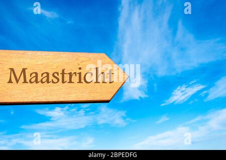 Wooden arrow sign pointing destination MAASTRICHT, The Netherlands  against clear blue sky with copy space available. Travel destination conceptual im Stock Photo