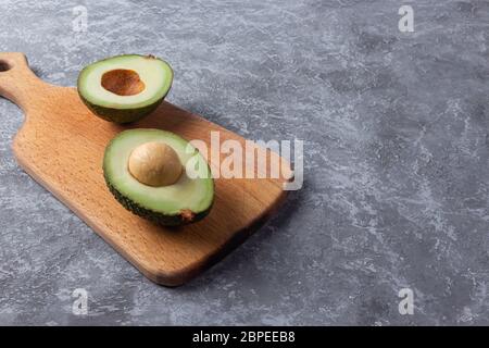 Avocado cooking recipes. Ripe green avocado on a wooden cutting board serving. Stock Photo