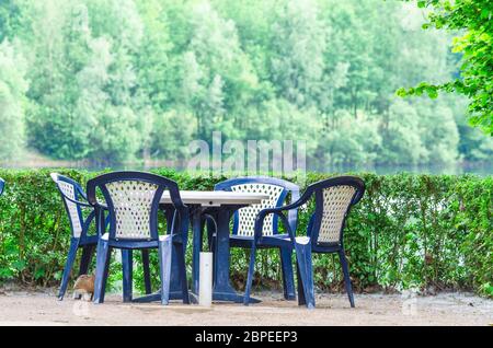 Einfache blaue Kunststoff Stühle und Tisch auf einer Terrasse mit Seeblick.