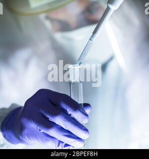 Life scientist researching in laboratory. Focused life science professional pipetting human serum media containing HIV infected cells. High protection Stock Photo