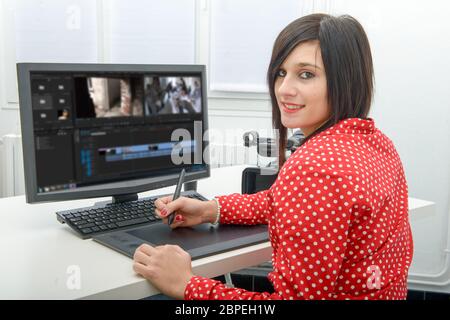 young brunette female designer using graphics tablet for video editing Stock Photo