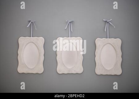 Three empty frames hanged on a grey wall Stock Photo