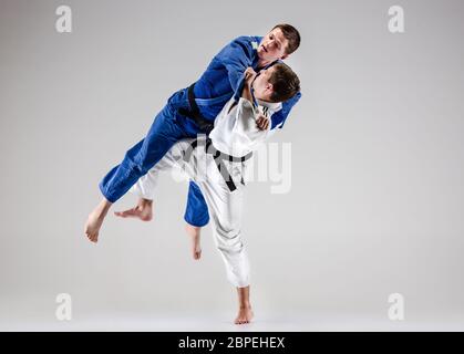The two judokas fighters fighting men on gray studio background Stock Photo