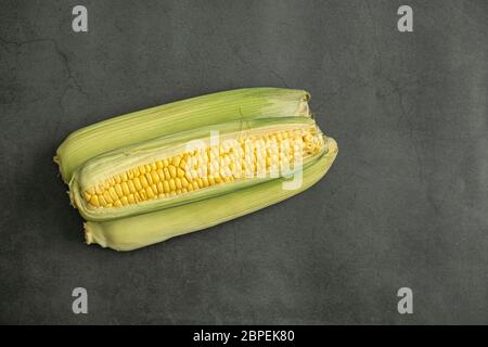 Fresh raw corn cobs on concrete, stone background. Tasty, healthy and organic food. Top view, flat lay composition. Stock Photo