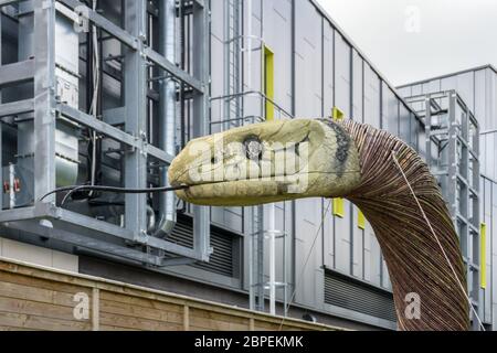 Snake sculpture made of cane and wood in front of a modern industrial building, Rushden Lakes shopping centre, Northamptonshire, UK Stock Photo