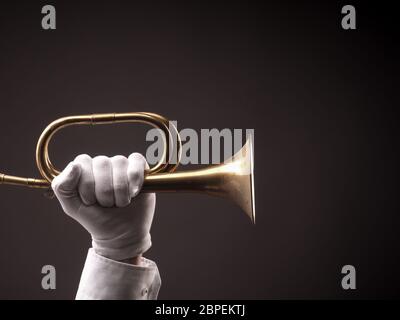 Hand with white gloves holding an old dusty trumpet on a dark background Stock Photo