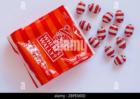 Packet of M&S Where's Wally foiled solid milk chocolate mini eggs opened with contents spilled spilt isolated on white background Stock Photo