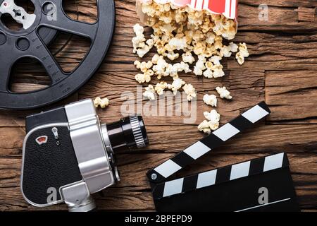Closeup of movie camera with film reel  clapper board and popcorn on wood Stock Photo
