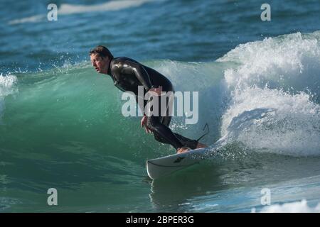 A mature male surfer riding a wave at Fistral in Newquay in Cornwall. Stock Photo