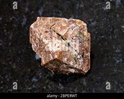macro shooting of natural mineral rock specimen - crystal of Zircon gemstone on dark granite background from Marchenko Peak, Khibiny Mountains, Kola P Stock Photo