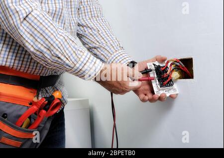 Electrician at work on switches and sockets of a residential electrical system. Stock Photo
