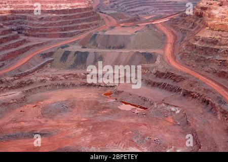 Large, open-pit iron ore mine showing the various layers of soil and iron rich ore