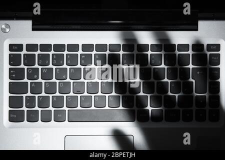 High Angle View Of Human Hand's Shadow Falling On Laptop Keypad Stock Photo